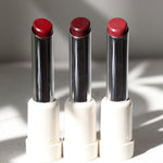 Three vegan lipsticks multisticks in red shades, each with a silver and white packaging, displayed side by side.