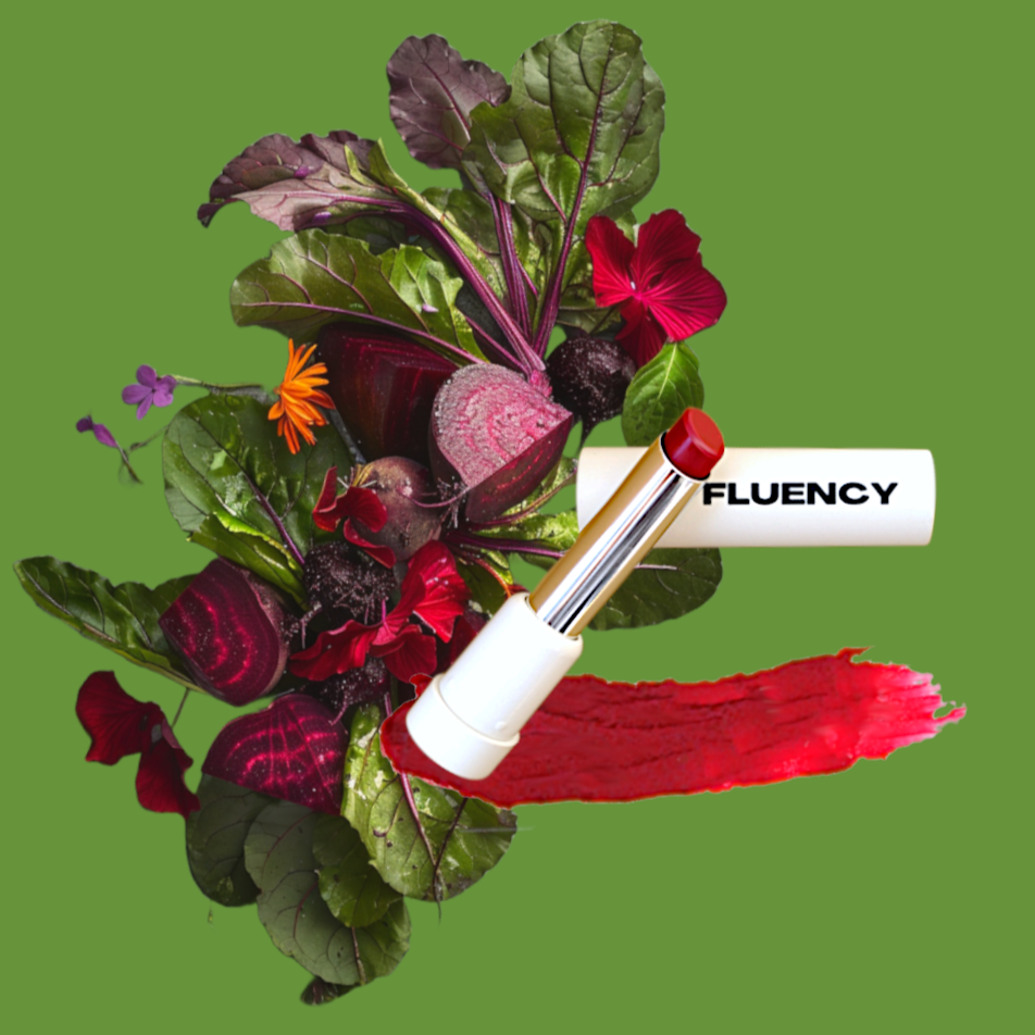 Fluency stick of multi-purpose vegan cosmetic product displayed alongside a vibrant assortment of vegetables and herbs, symbolizing the product's natural ingredients. Colored from beets and potatoes.
