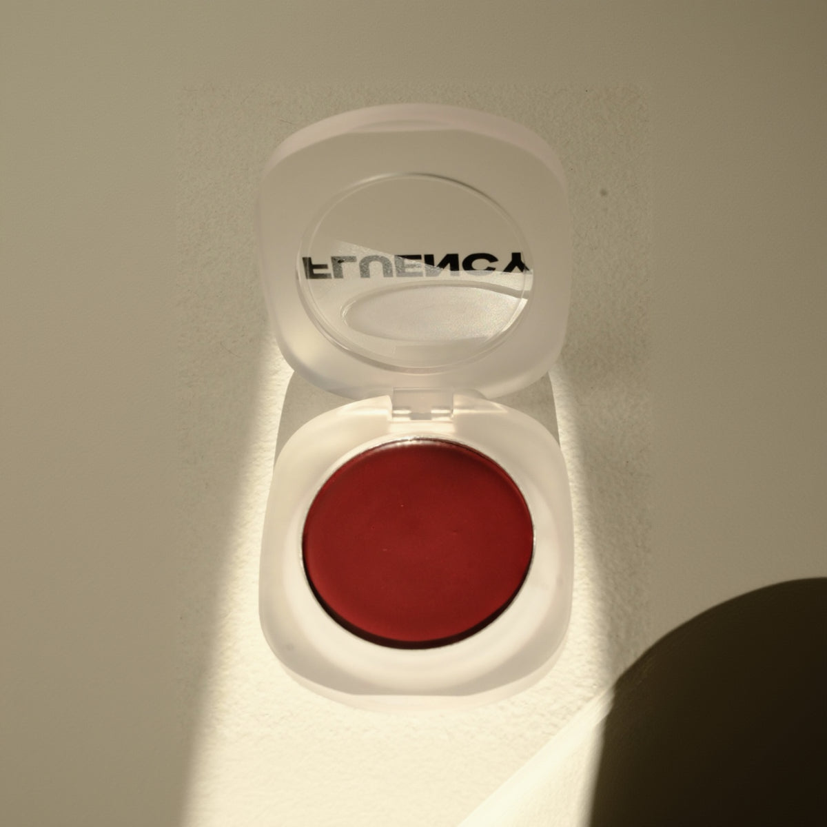 Red makeup compact with 'Fluency' branding on a light background, clean blush palette, vegan, plant-based