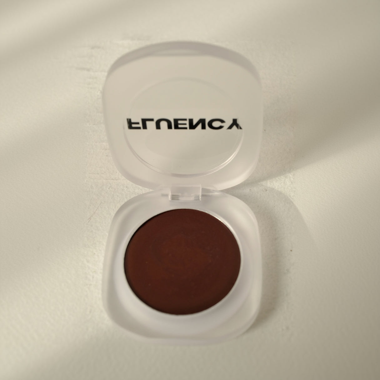 Brown vegan, plant-based makeup compact with 'Fluency' branding on a light background. Clean blush makeup