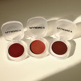 Three open cosmetic containers with red contents and 'Fluency branding on a light background. Vegan Beauty and makeup blush.