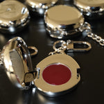 Fluency silver chrome keychain charm open showcasing red cream makup inside