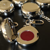 Fluency silver chrome keychain charm open showcasing red cream makup inside