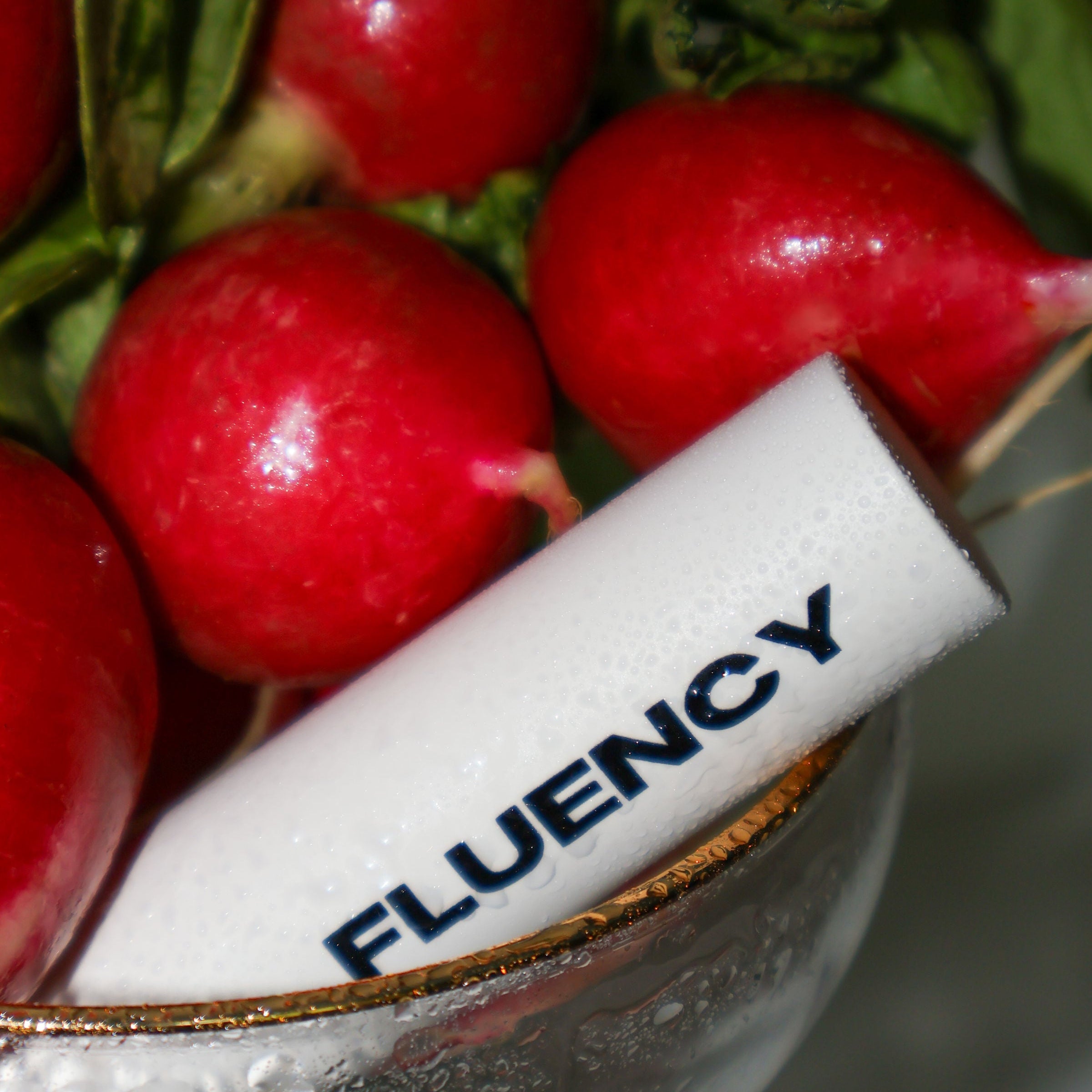 Red radishes in a bowl with a 'Fluency' product on top