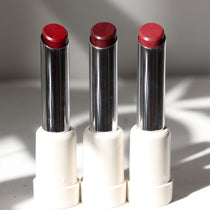 Three vegan lipsticks multisticks in red shades, each with a silver and white packaging, displayed side by side.