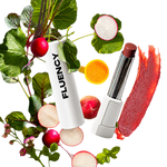 A white cosmetic tube labeled 'FLUENCY' is arranged with fresh radishes, red beets, green leaves, and a red lipstick smear on a white background.