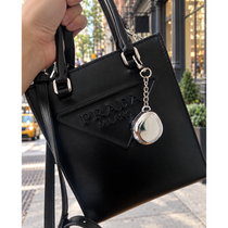 Fluency Color Me Ready silver chrome compact keychain attached to a black Prada bag on a New York City sidewalk